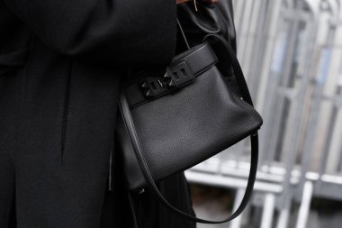 Paris, Fransa - 4 Ekim 2025: Kadınlar Hermes Medor marka siyah omuz çantası, şık kıyafet ayrıntıları ve sokak tarzı aksesuarlar giyerler. Moda şehri görünümü.