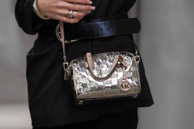 Paris, Fransa - 4 Ekim 2025: Kadın Michael Kors 'un altın çantasına monogram logo takıyor, sokak tarzı aksesuarlar