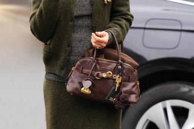Paris, Fransa - 6 Ekim 2025: Kadın Miu Miu Aventure kahverengi omuz çantası giyiyor. Moda kıyafet çantası detayı, sokak tarzı aksesuar.