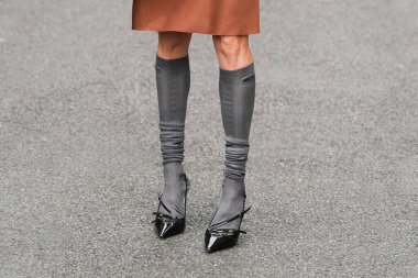 Paris, Fransa - 6 Ekim 2025: Kadınlar Miu Miu marka siyah topuklu ve gri diz boyu çoraplar giyerler. Sokak tarzı moda aksesuarları, şık şehir kıyafetleri..