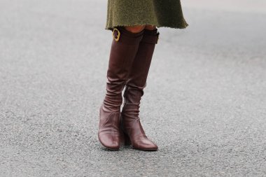 Paris, Fransa - 6 Ekim 2025: Kadınlar kahverengi Miu Miu deri diz boyu çizme giyerler. Moda kıyafetleri ayakkabılar, sokak tarzı aksesuar.