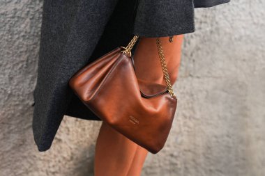 Milan, İtalya - 25 Eylül 2025: Kadın kahverengi Prada Tumulte nappa deri çanta giyiyor. Moda kıyafeti çanta ayrıntıları, sokak tarzı aksesuar.