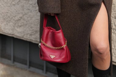 Milan, Italy - September, 25, 2025: woman wears Prada red Petite Sac Noir Mini Nappa leather bucket bag. Fashion outfit handbag details, street style look accessory
