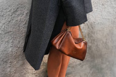 Milan, İtalya - 25 Eylül 2025: Kadın kahverengi Prada Tumulte nappa deri çanta giyiyor. Moda kıyafeti çanta ayrıntıları, sokak tarzı aksesuar.