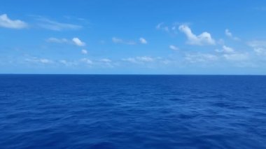 Mavi deniz, güzel mavi gökyüzü ve boş ufuk altında küçük bir dalga. 