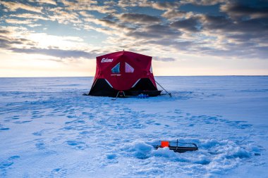 Brooks Alberta Canada, February 20 2020:  An ice fishing tent sits on Lake Newell during late winter as fishermen jig for Northern Pike. clipart