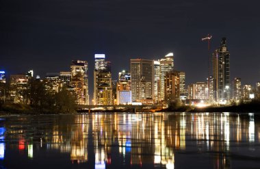 Calgary şehir merkezi ofis ışıkları gece Bow River 'ı yansıtıyor..