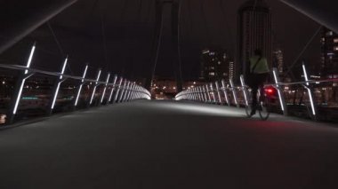 İşe gidip gelen bir bisikletçi, Calgary Alberta Kanada 'daki Bow Nehri üzerinden yaya köprüsünden gece geçiyor..