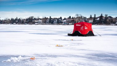 Chestermere Alberta Canada, Ocak 04 2021: Alberta Kanada 'daki donmuş Chestermere Gölü' nde Kuzey Pike balıkçılığı için bir Eskimo buz balıkçılığı çadırı ve ipuçları.