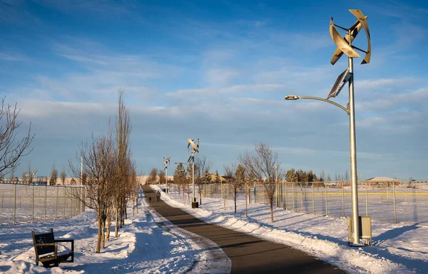 Modern vertical wind turbines with a solar panels on a light poles producing renewable energy for the green technology industry at a park in Airdrie Alberta Canada.