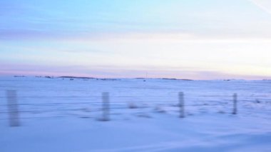 Rocky View County Alberta Canada 'da karla kaplı tarım arazileri olan dikenli tel çitlerin yanından geçen çayır..