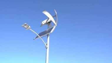 A solar powered wind turbine spinning while recharging a LED street light.