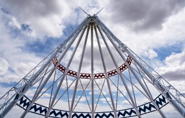 Medicine Hat Alberta Canada, May 14 2021: The worlds tallest tepee indigenous display standing against a dramatic sky at a Alberta travel information centre.