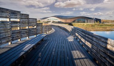 Calgary Alberta Kanada, 12 Mayıs 2021: Rocky Ridge YMCA spor tesisinin tahta tahta kaldırım köprüsü Kanada 'nın doğal yaşam alanının üzerinden geçiyor..