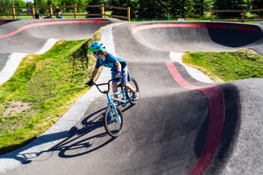 Calgary Alberta Canada, 20 Haziran 2021: Bir yaz akşamı Calgary Alberta Kanada 'da Güney Glenmore Park BMX pompa pistine binen genç bir çocuk.