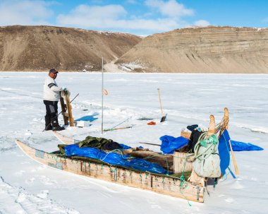 QAANAQ, GREENLAND, Grönlandlı adam donmuş denizde buzda balık tutuyor