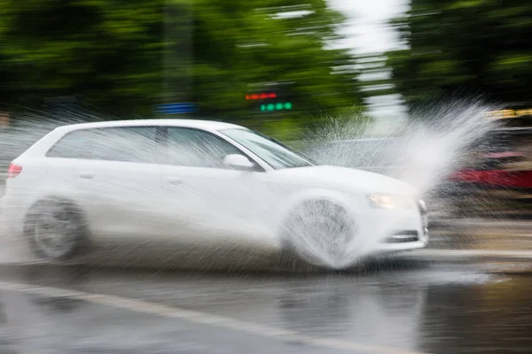 View of fast speed car entering a puddle and moment of splashing water to the sides
