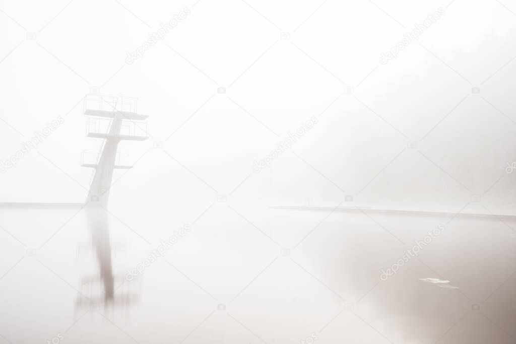 Tiered diving boards in a lake in thick fog