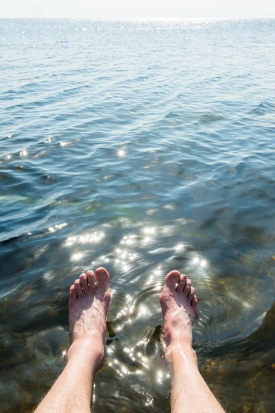 輝く湖の上の男の足のクローズアップ — ストック写真