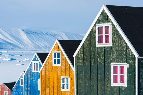 一排五彩斑斓的木头房子映衬着一片雪地 — 图库照片