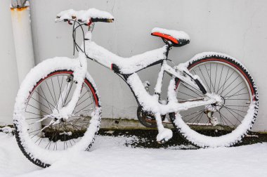 Karla kaplı bisiklet duvara yaslanıyor.