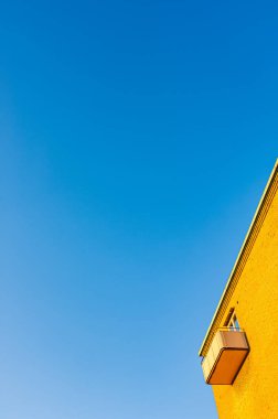 Balkonlu ve mavi gökyüzlü sarı bir bina manzarası 