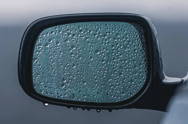Arabanın aynasında su damlaları var.
