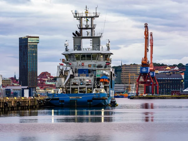Bir İsveç sahil güvenlik gemisi Gothenburg limanına güvenli bir şekilde yanaştı, şehir manzarası ile çevrili. Sakin sular ufuk çizgisini yansıtıyor, yakınlardaki gökdelenleri ve vinçleri gösteriyor..