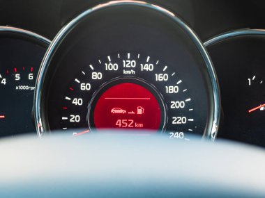 Gösterge paneli modern bir arabadaki hız göstergesi ve yakıt göstergesinin yakın çekimini gösteriyor, mevcut hızı ve kalan yakıtı kilometrelerce olarak vurguluyor..