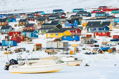 Tekneler, Grönland, Qaanaaq 'daki renkli binaların yakınlarındaki karda dinleniyor. Bu köy yerel sakinlere ev sahipliği yapıyor ve Kuzey Kutbu bölgesindeki yaşamı yansıtıyor. Bölgeyi kış manzarası kaplıyor.