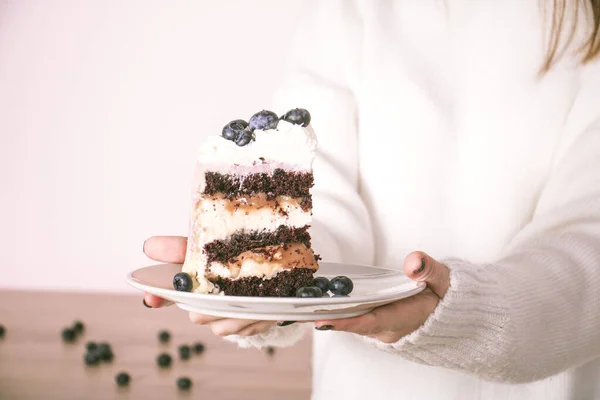 白いセーターの女の子は手にブルーベリーとケーキとプレートを保持しています — ストック写真
