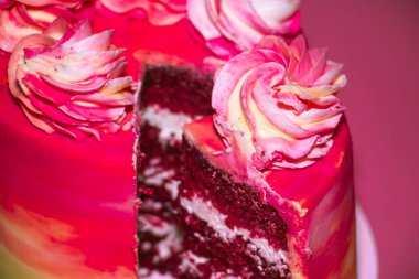 Pembe arka planda pembe ve sarı kremayla süslenmiş dilimlenmiş sünger kek.