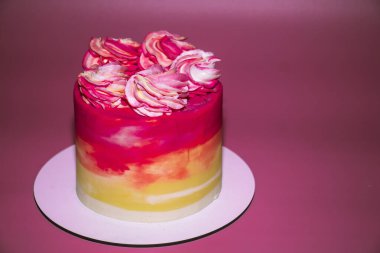 Pembe arka planda pembe ve sarı kremayla süslenmiş sünger pastası.
