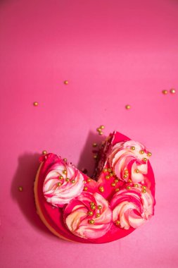 Pembe arka planda pembe ve sarı kremayla süslenmiş dilimlenmiş sünger kek.