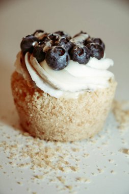 Beyaz arka planda kremalı ve yaban mersinli kek.