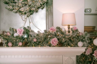 Beyaz şöminede oyuncakları olan yapay Noel ağacı dalı