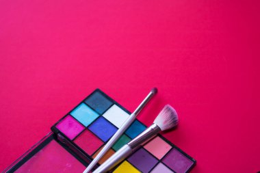 Pembe arka planda makyaj fırçaları ve paletler