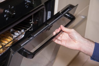 Adam fırındaki yiyecekleri kontrol ediyor.