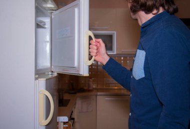 Adam yiyecek bulmak için buzdolabını açtı.