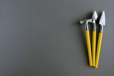 Minyatür bahçe malzemeleri, aletler, tırmıklar, kürekler. Bitki bakımı. Gri ve sarı, Panton 2021. Gri arka plan. Metin için boşluk.