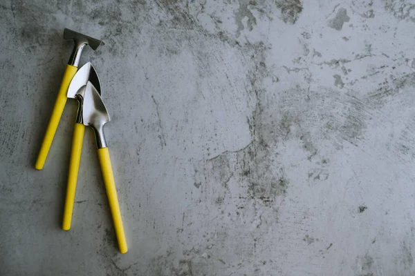 Miniature garden supplies, tools, rakes, shovels. Plant care. Grey and yellow, Panton 2021. Gray background. Space for text.