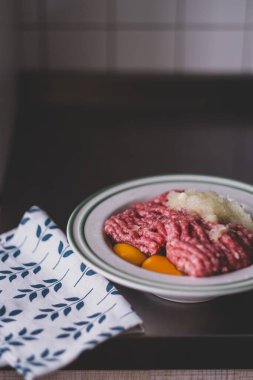 Mutfak masasında kıyma, çiğ tavuk yumurtası ve soğan. Pirzola, etli turta, köfte ve köfte malzemeleri. Besleyici sağlıklı öğle yemeği, protein yiyeceği, tarım ürünleri, evde yemek pişirme.