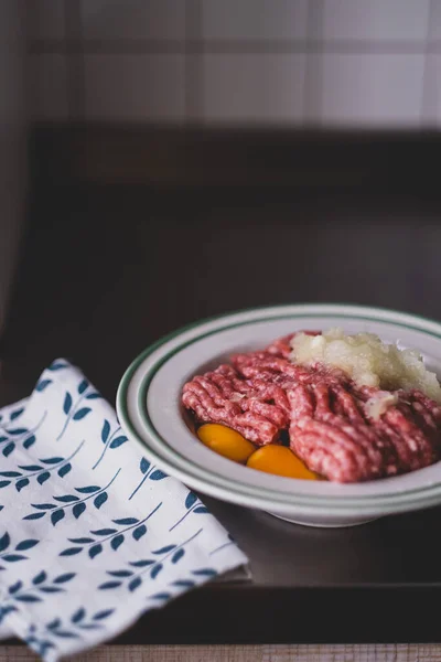 minced pork, raw chicken eggs and onions in a white plate on the kitchen table. ingredients for cooking cutlets, meat pie, meatballs and meatballs. Nutritious hearty lunch, protein food, farm products, cooking food at home