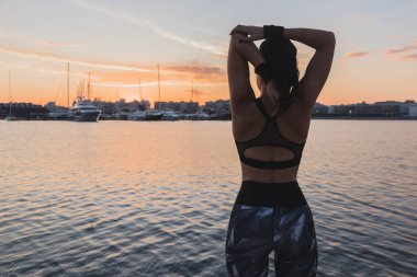 Gün batımında şapkası gerinen koşucu kız