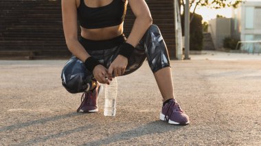 Koşucu kız bir şişe suyla dinleniyor.