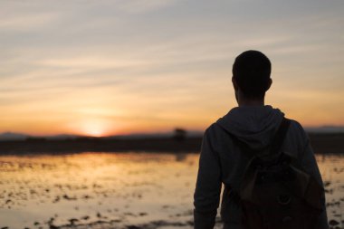 Sırt çantası ve gün batımı olan bir adam.