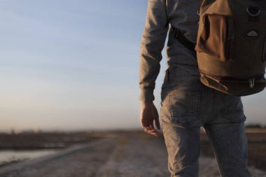 Sırt çantası ve gün batımı olan bir adam.