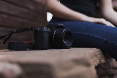 Kız kamerayla güneşin altında oturuyor.