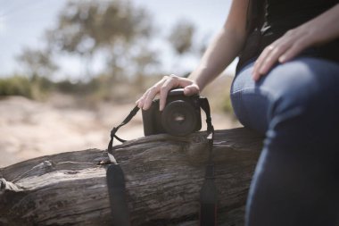 Kız kamerayla güneşin altında oturuyor.