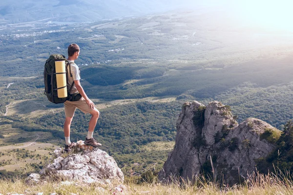 Mochilero en la roca y mirando el gran valle — Foto de Stock